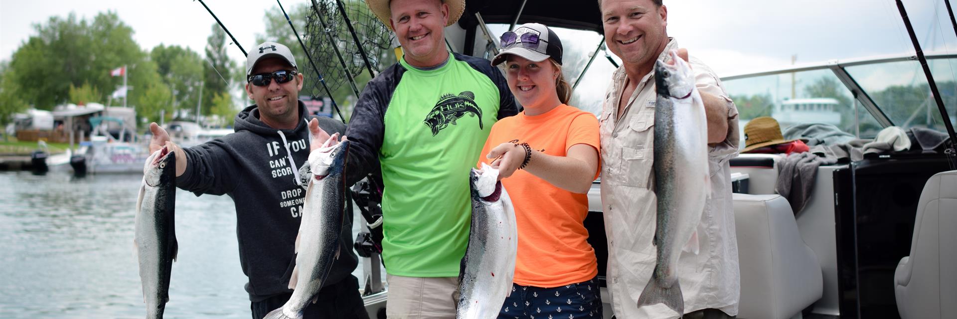 people holding up recently caught fish on the back of a boat in Chatham-Kent